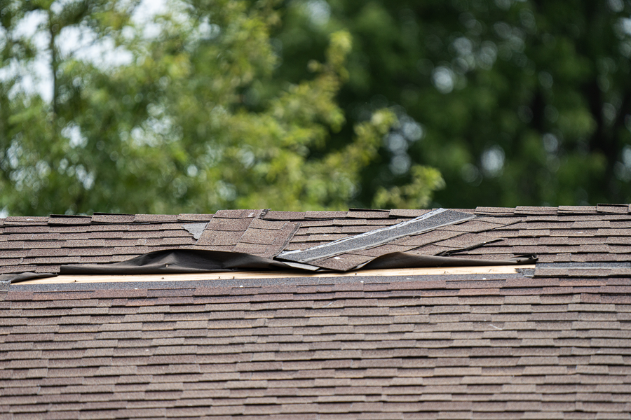 Roof on house with damaged shingles.