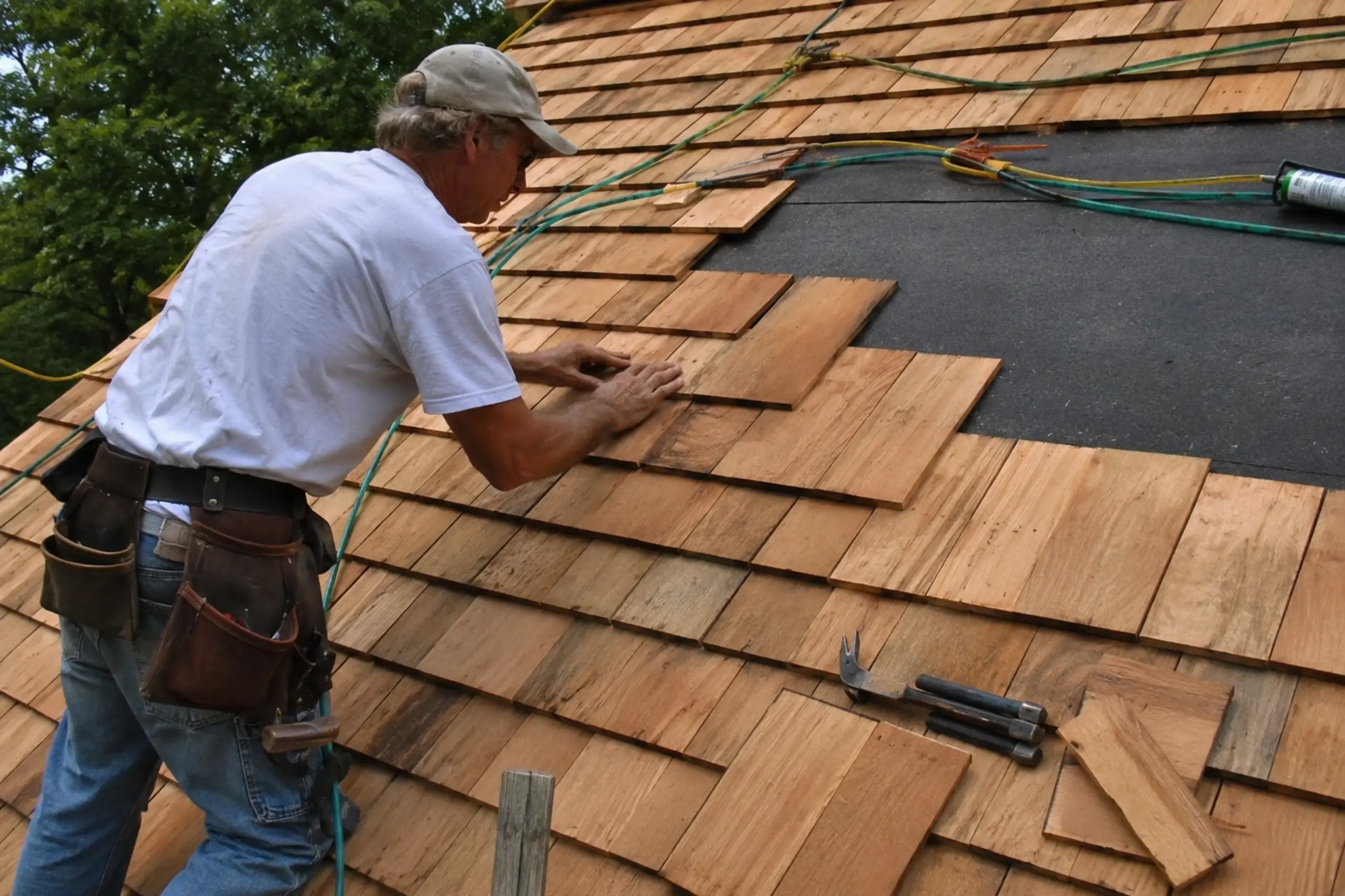 Roofer installing natural wood shakes on a residential roof during a roofing project.