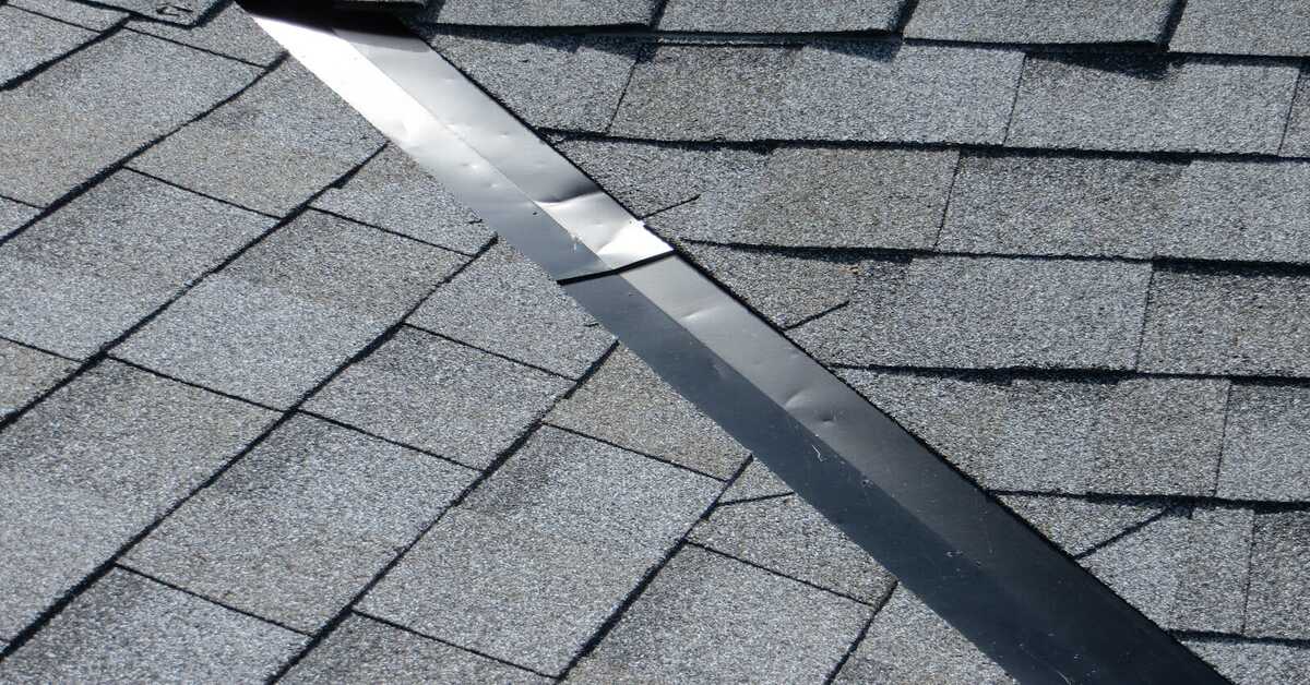 Close-up of roof valley flashing installed between asphalt shingles.