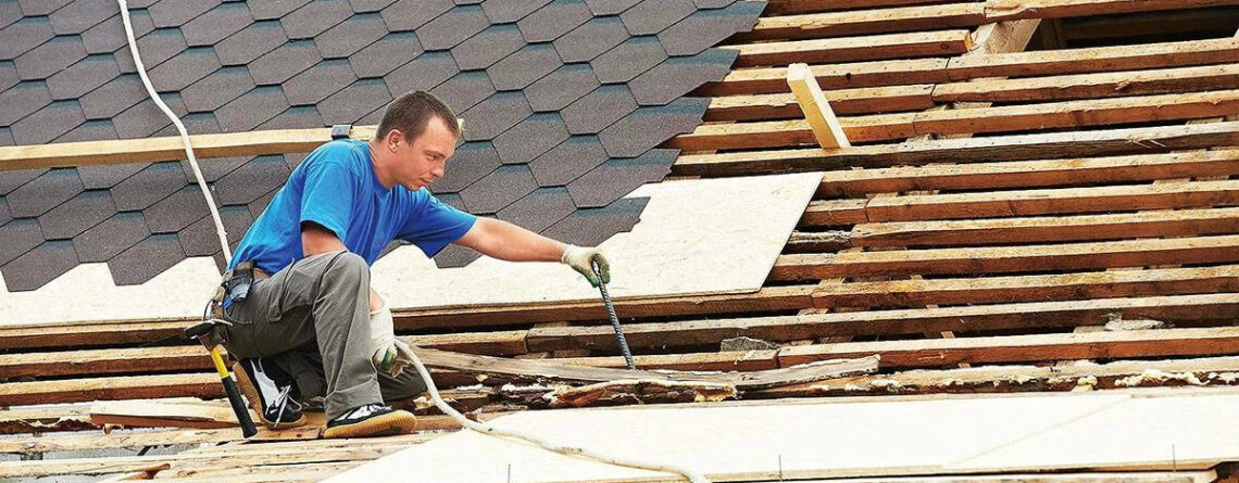 Roofer installing shingles and repairing roof decking.