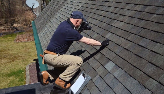 Roofer inspecting asphalt shingles for signs of roof leaks.