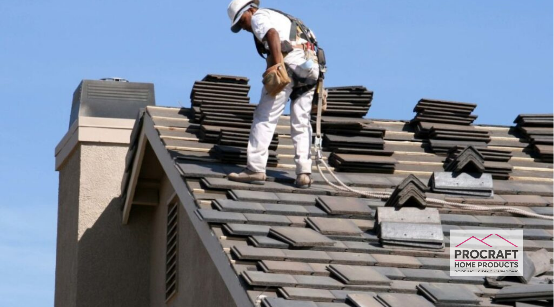 Worker installing roof tiles on a sloped roof.